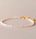 Minimal flat lay close-up showing classic pearl bracelet in natural color with delicate small pearls and gold clasp detail