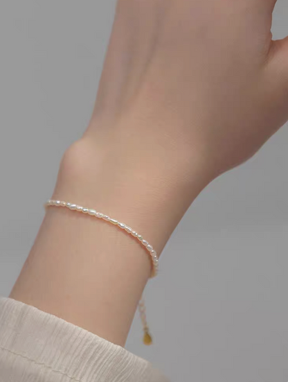 Lifestyle photo showing classic pearl bracelet in natural color worn on wrist, minimalist everyday styling with delicate pearls