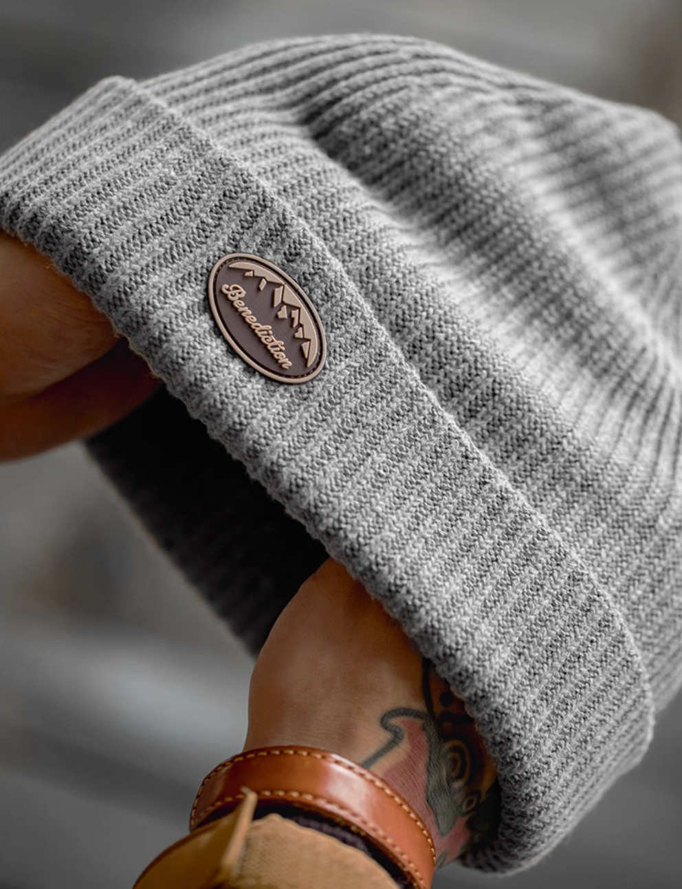 Close-up of Classic Ribbed Knit Beanie with Logo Detail in gray showing soft ribbed knit texture and embossed logo patch on folded brim