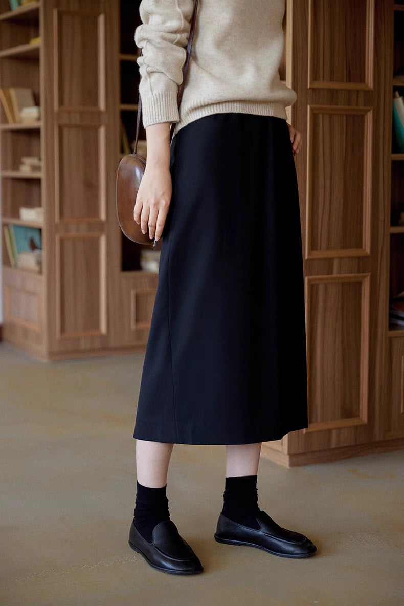 Close-up front detail of The Classic Sculpted Midi Skirt in black showing smooth structured fabric and elegant straight silhouette