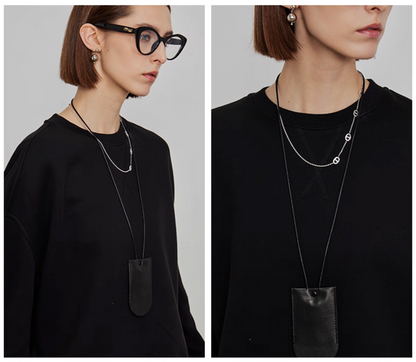 Closeup of neckline and layered necklace on women’s oversized black sweatshirt
