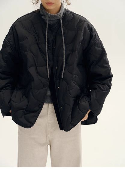Close front view of black oversized H-line quilted down jacket with raglan sleeves.