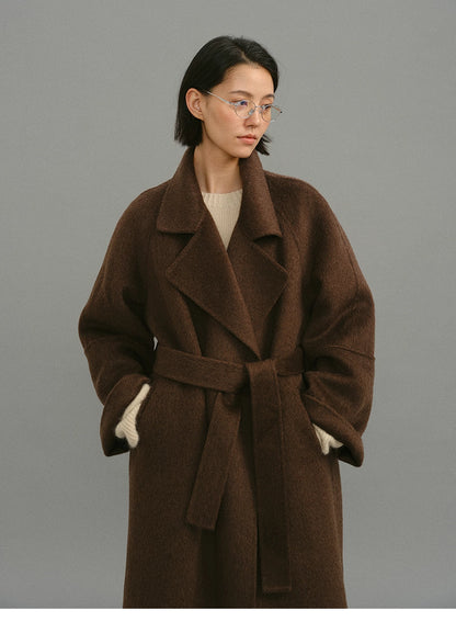 Dark coffee camel-blend coat shown belted from the front with wide lapels.