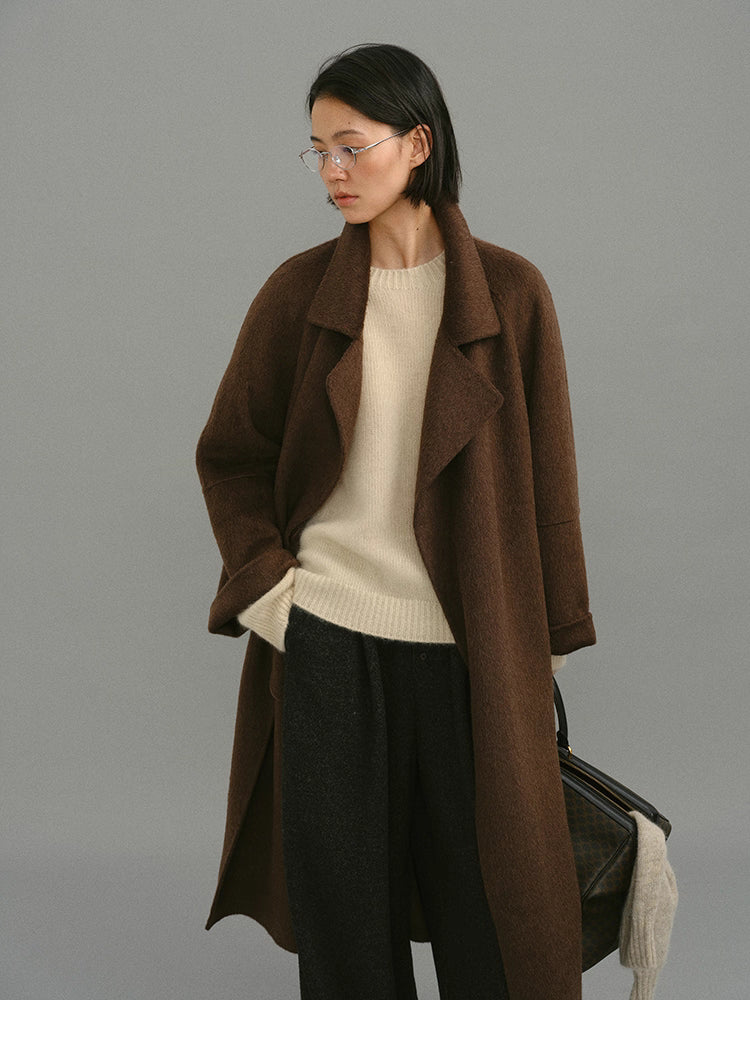 Model wearing camel-blend wrap coat open over cream sweater and dark trousers.