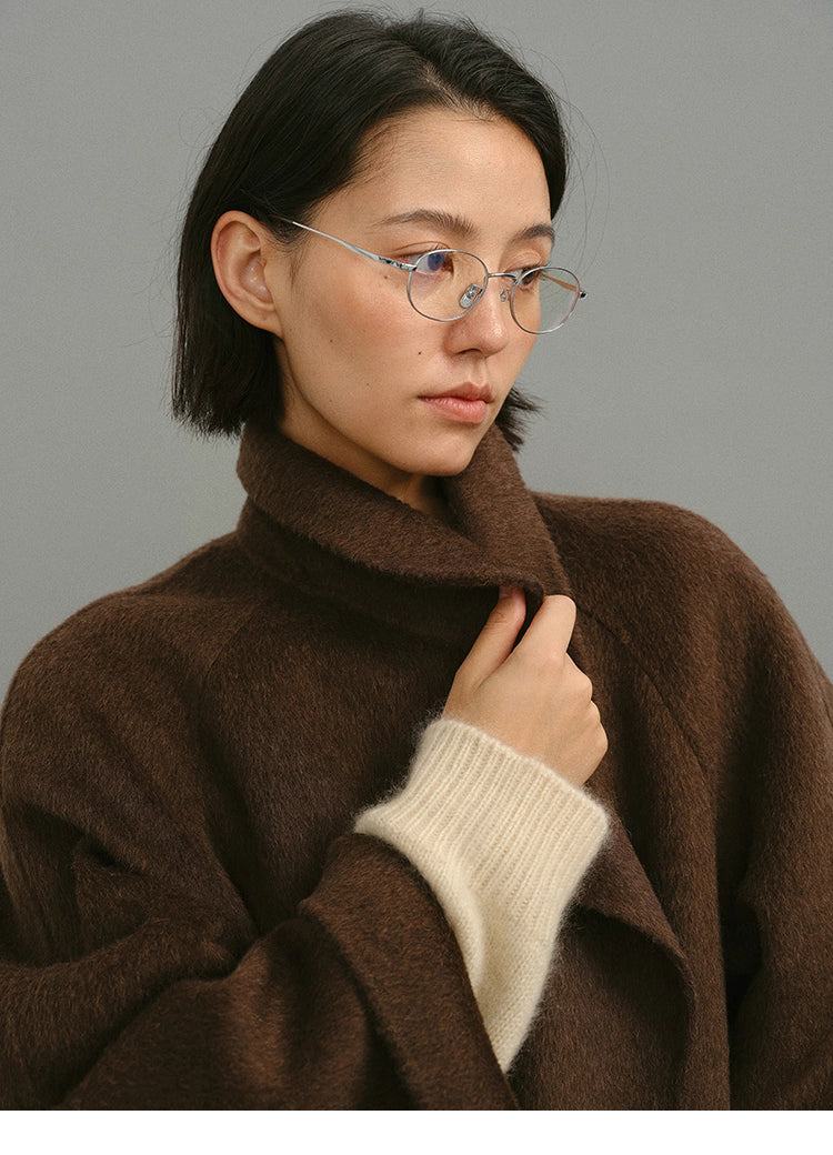 Close-up of plush camel-wool-silk texture and collar with cream knit cuff detail.