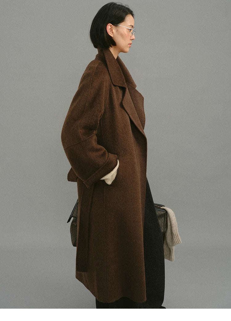 Side profile showing drape, dropped shoulder and longline silhouette of coat.