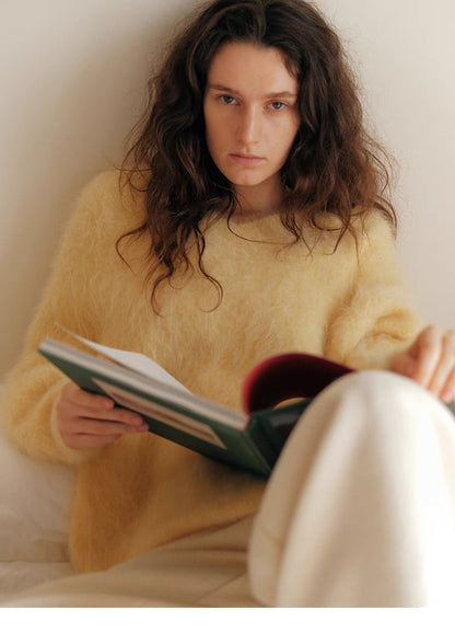 Cream yellow wool sweater close up reading book highlighting fluffy knit texture and V neck detail