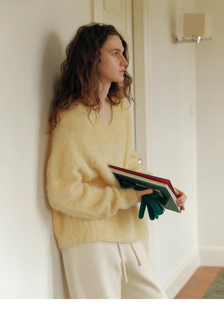 Cream yellow brushed wool sweater side view holding books showcasing relaxed silhouette and soft airy fabric