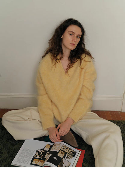 Cream yellow brushed wool sweater sitting on floor with open book showing cozy relaxed fit and soft texture
