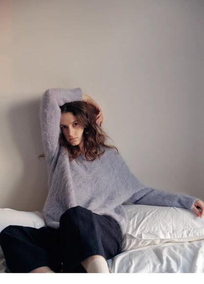 Misty blue brushed wool sweater lounging on bed showcasing relaxed fit and airy soft texture
