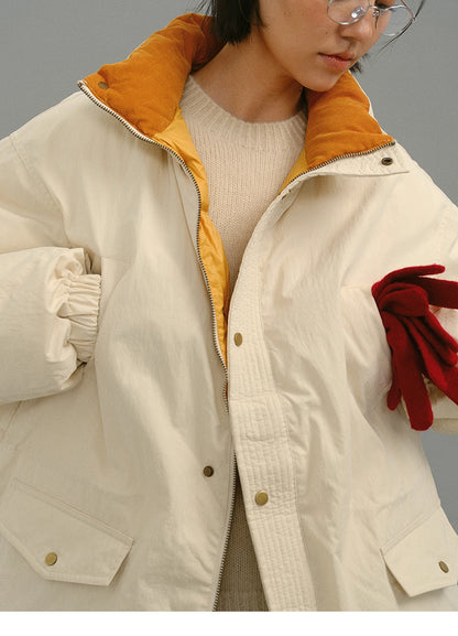 Close-up of cream yellow coat showing mustard collar texture and the model holding red gloves.
