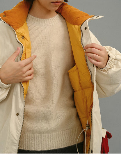 Model opening the cream yellow coat to reveal the mustard quilted inner lining and beige sweater.