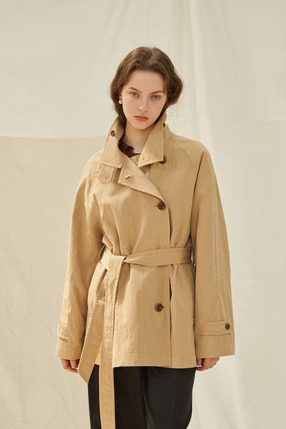 Light brown coastal journey trench coat front view with belt tied, structured collar and relaxed fit