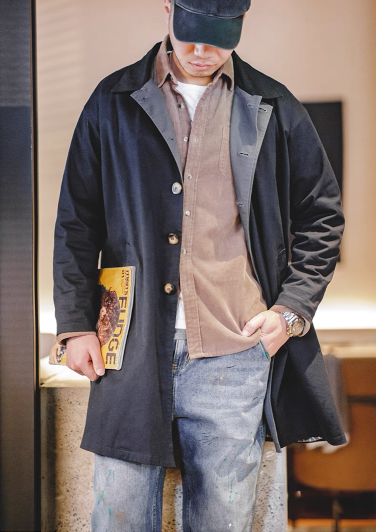 Men’s navy blue trench coat layered over brown overshirt and jeans – urban smart casual outfit.