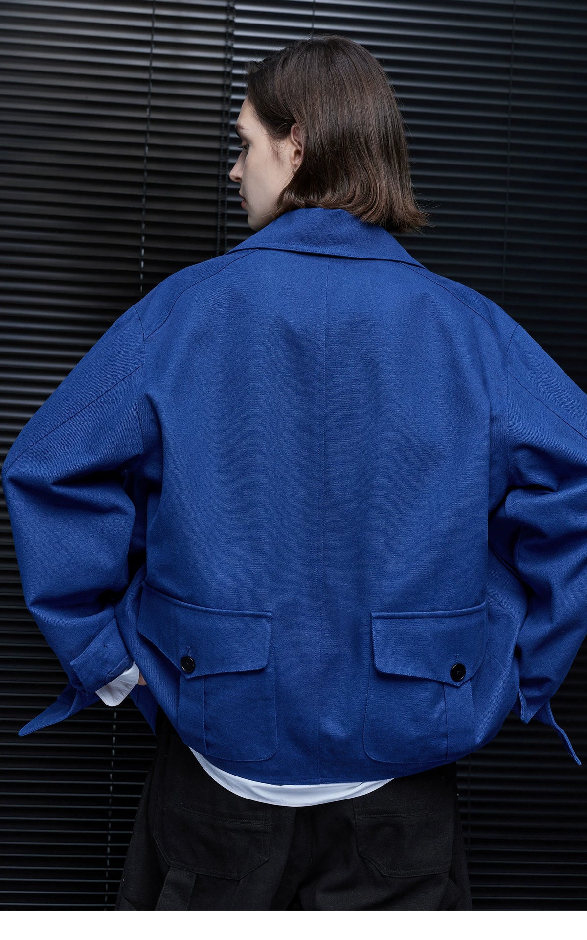 Back view of a Cobalt Blue chore jacket showing two buttoned flap pockets and cuff tabs