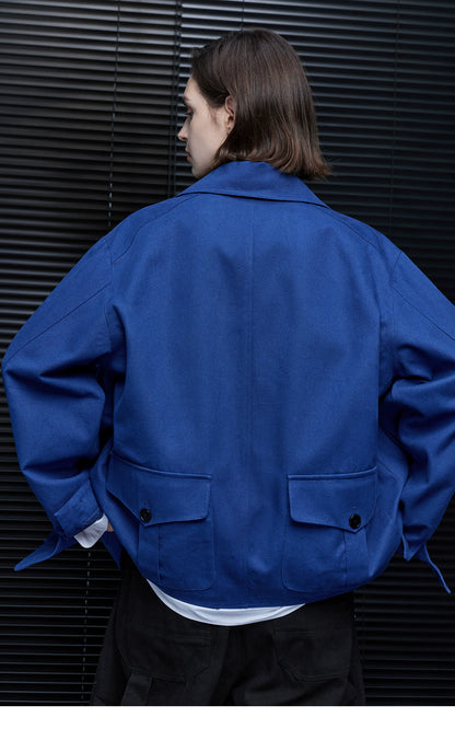 Back view of a Cobalt Blue chore jacket showing two buttoned flap pockets and cuff tabs