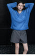Front view of Cobalt Blue sweater showing hand-crocheted 3D flowers across the body, arms raised