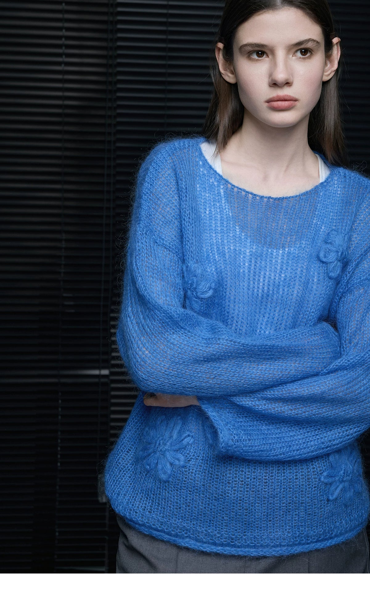 Woman in Cobalt Blue sheer knit sweater with crocheted flowers layered over a white tank, arms crossed