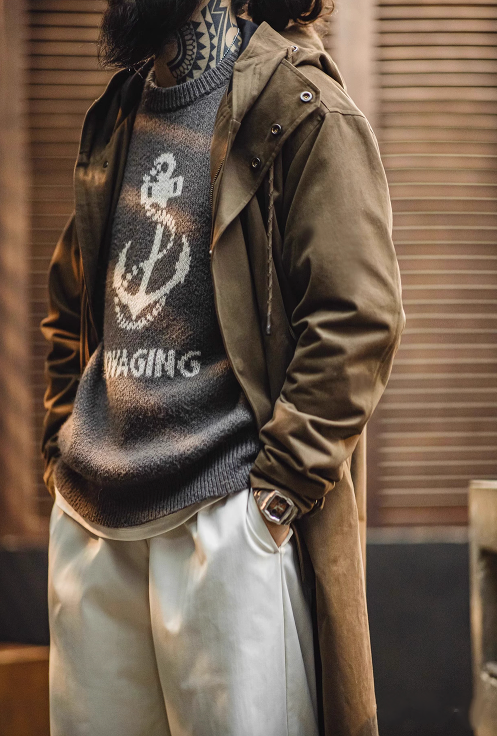 Model wearing Coffee Brown Cotton Windbreaker Coat in army green side view layered over sweater highlighting relaxed fit and pocket design