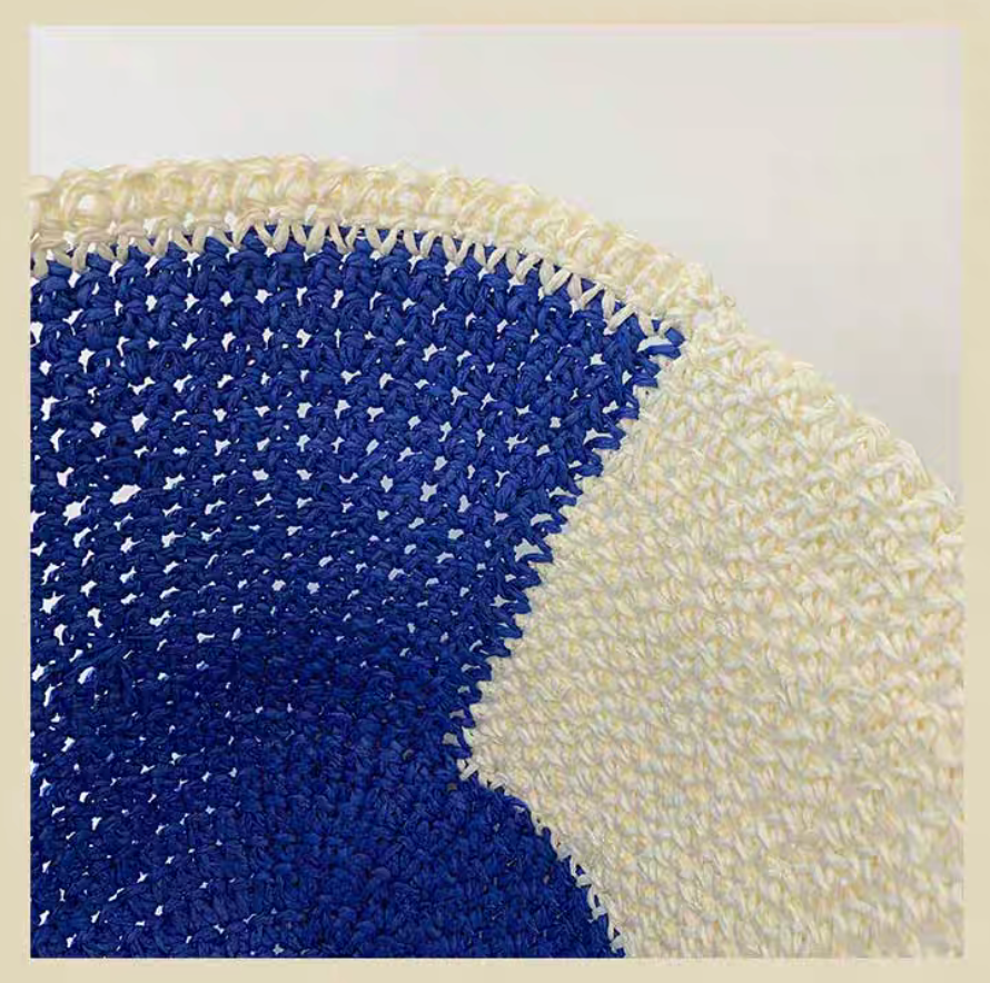 Close-up detail of white and blue straw bucket hat showing woven texture and stitching