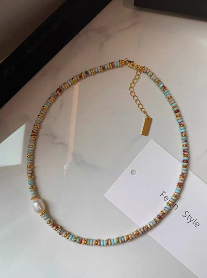 Full view of Colorburst jade and pearl necklace with multicolor natural stone beads, freshwater pearl detail, and gold-plated clasp on marble surface