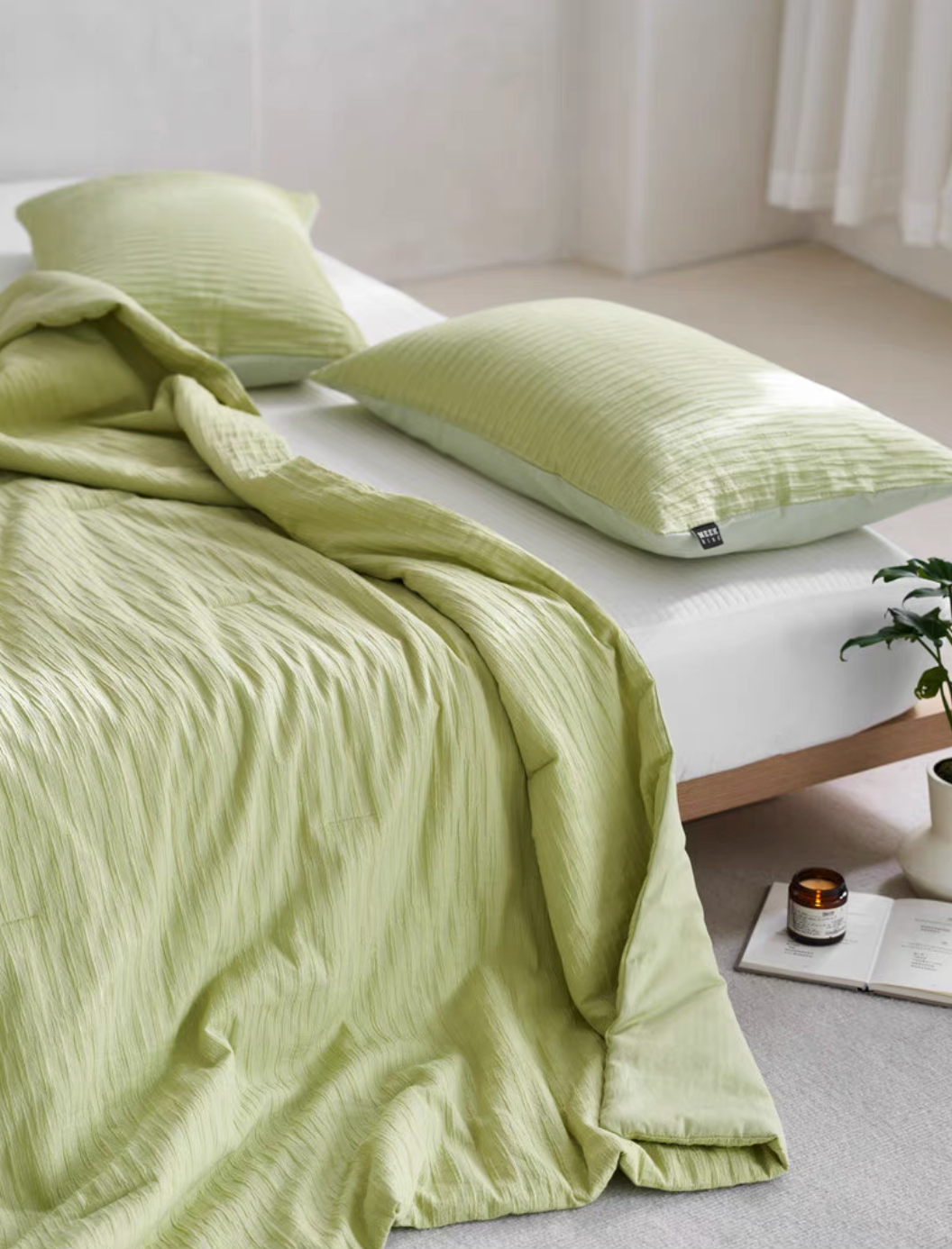Green Colorful cotton comforter and sham set close-up with textured pillow sham and softly draped bedding