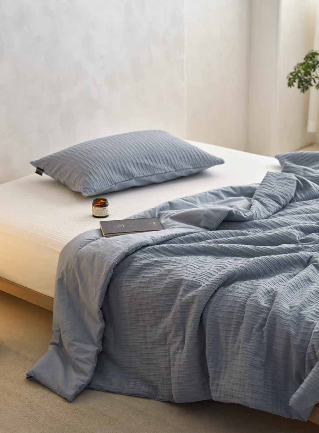 Navy Blue Colorful cotton comforter and sham set draped across bed with candle and book beside pillow sham