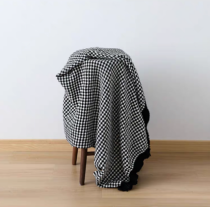 Black and white checkered throw blanket draped over chair, stylish textured knit home decor accent