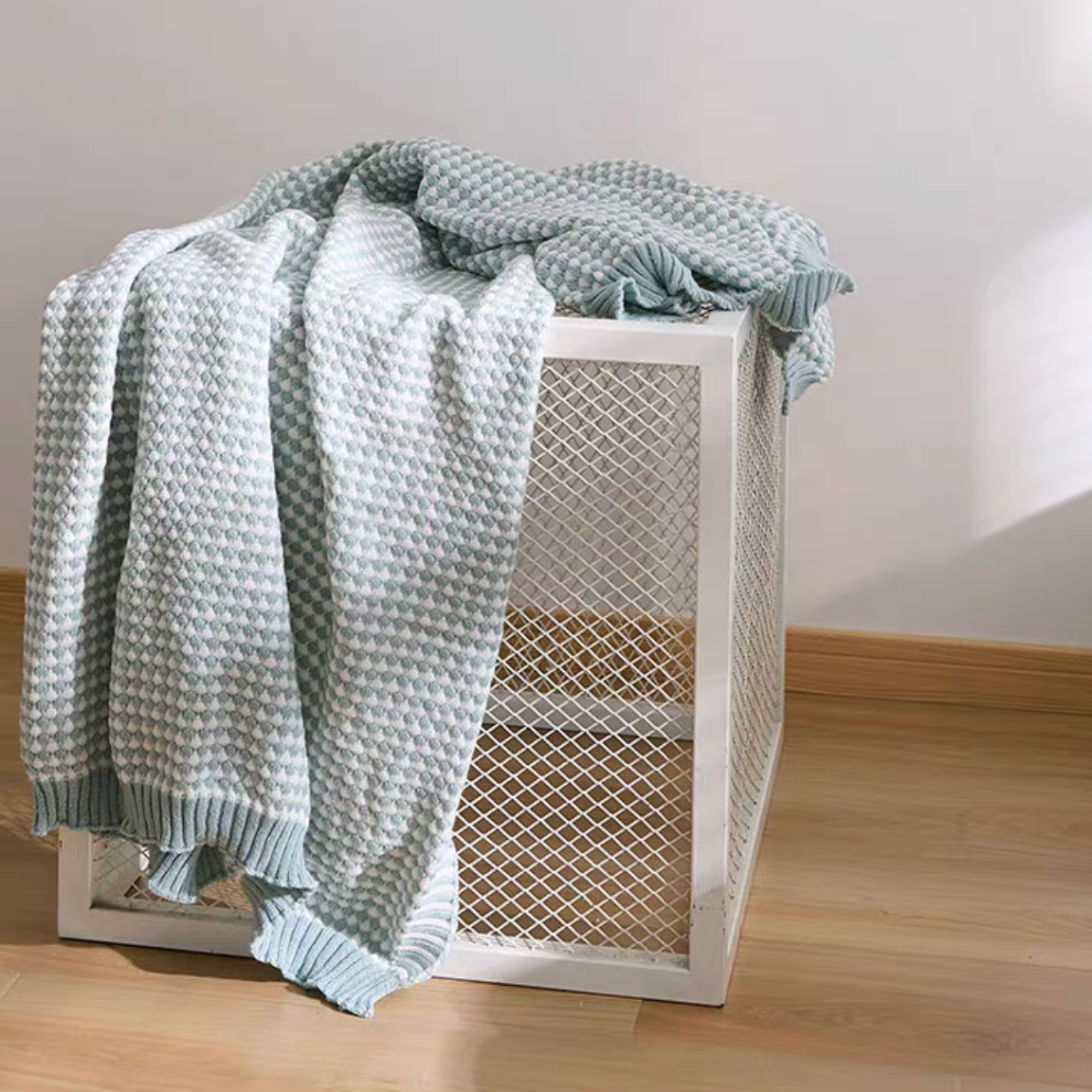 Light green checkered acrylic knit throw blanket draped over storage box, fresh minimal home styling