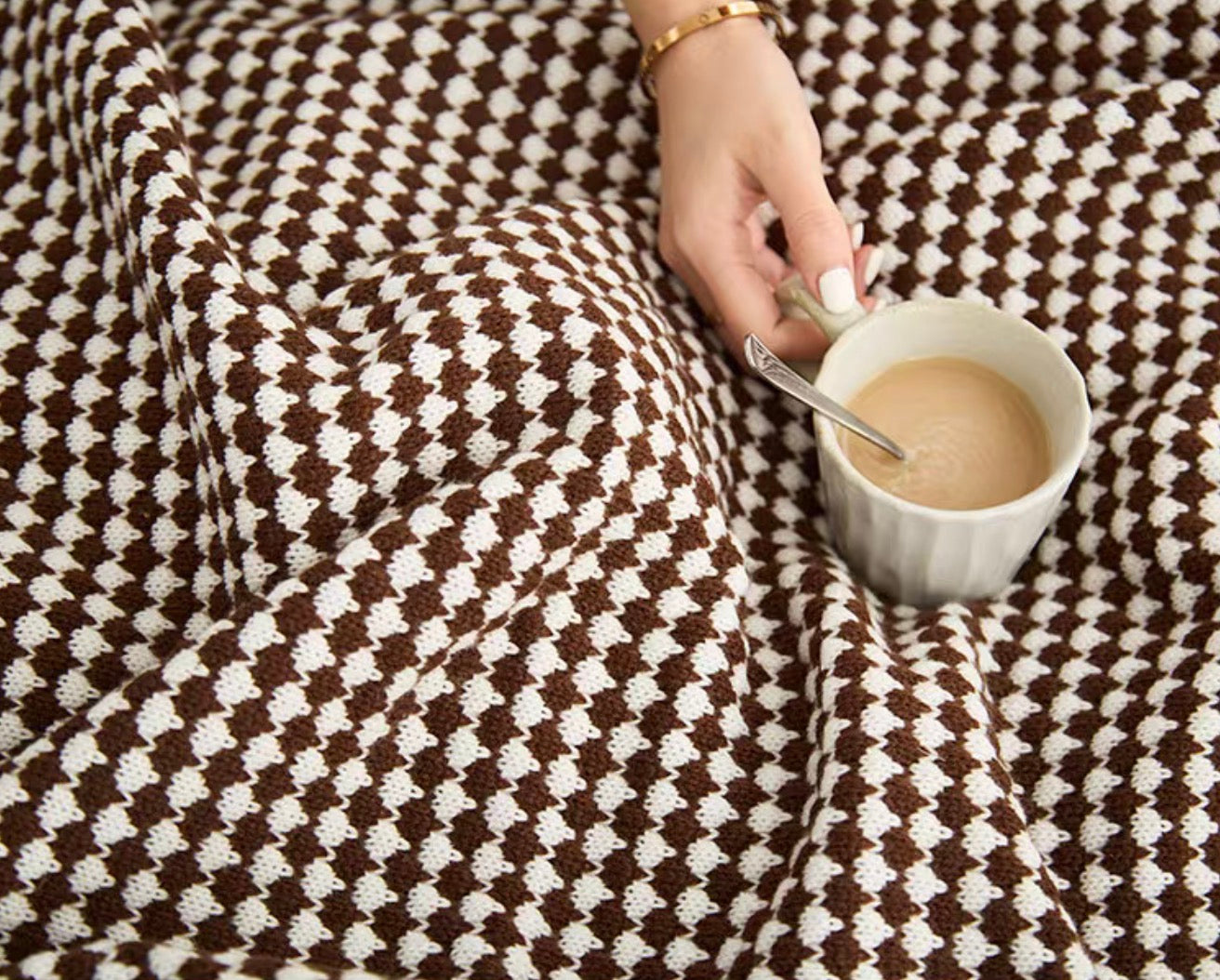 Close-up of mocha acrylic knit throw blanket with coffee cup, detailed soft textured fabric view