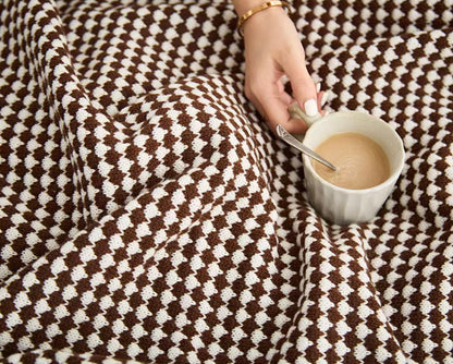 Close-up of mocha acrylic knit throw blanket with coffee cup, detailed soft textured fabric view