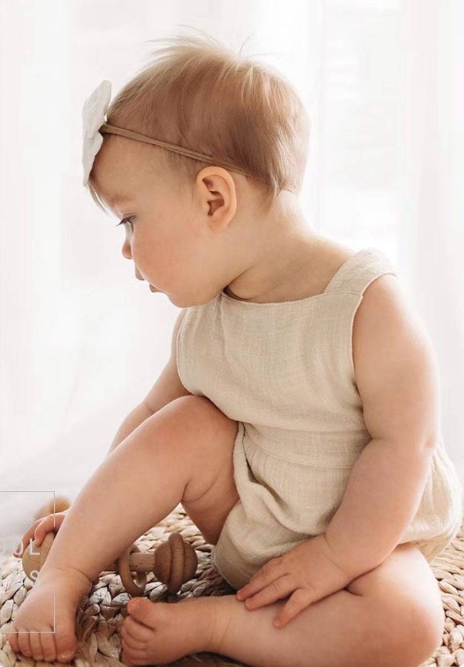 Baby wearing beige cotton gauze romper soft breathable sleeveless outfit comfortable summer lifestyle view