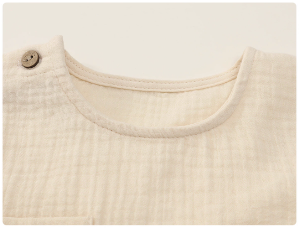 Close up of beige gauze cotton baby set neckline soft breathable fabric texture detail