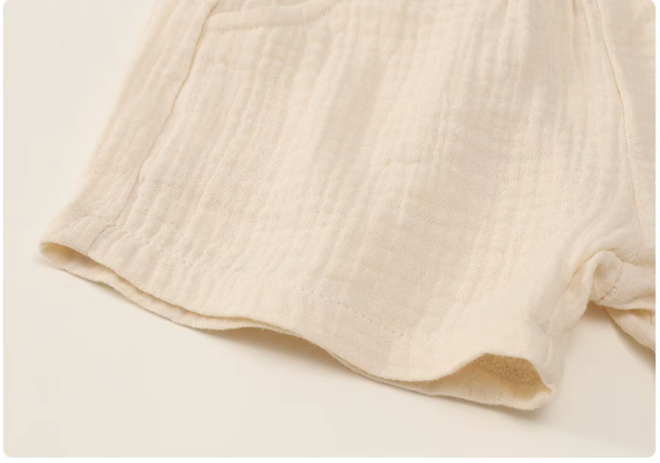 Beige gauze cotton baby shorts hem detail soft breathable fabric texture close up