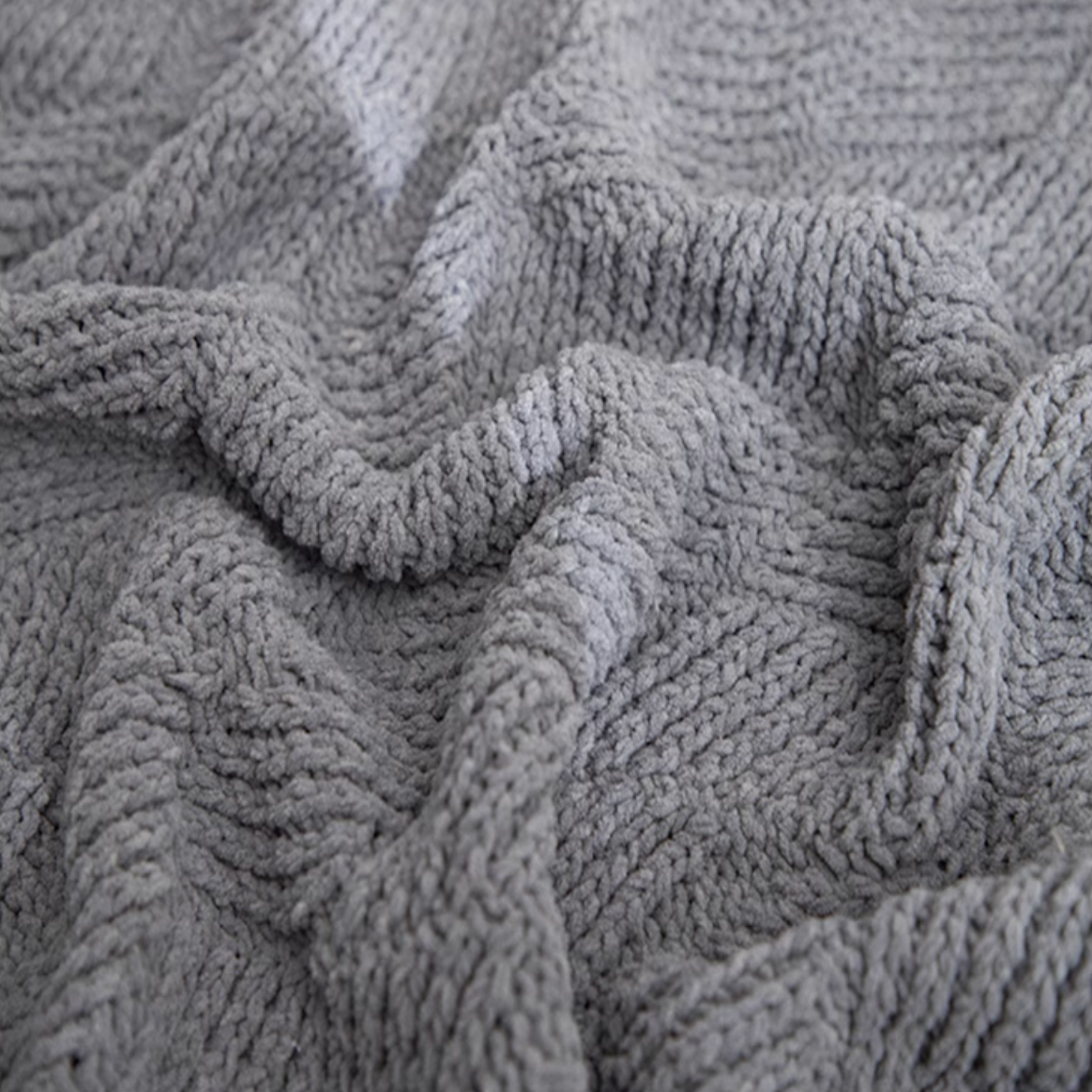 Close-up of gray chenille cable knit throw blanket highlighting plush fibers and detailed cable knit structure
