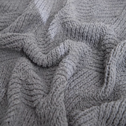 Close-up of gray chenille cable knit throw blanket highlighting plush fibers and detailed cable knit structure
