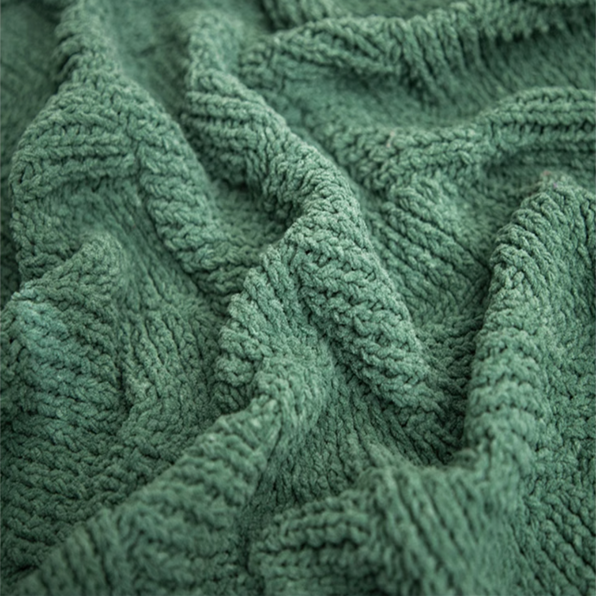 Close-up of green chenille cable knit throw blanket highlighting thick yarn texture and soft woven cable design