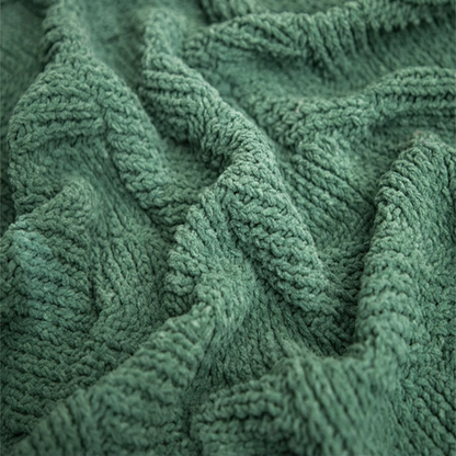 Close-up of green chenille cable knit throw blanket highlighting thick yarn texture and soft woven cable design