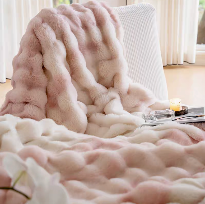 Ombre pink plush faux fur blanket draped over chair with candle and tray, ultra soft sculpted texture cozy decor