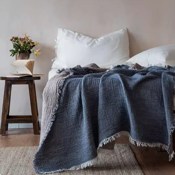 Gray khaki reversible cotton gauze throw blanket draped across bed with fringe edge, lightweight breathable summer blanket