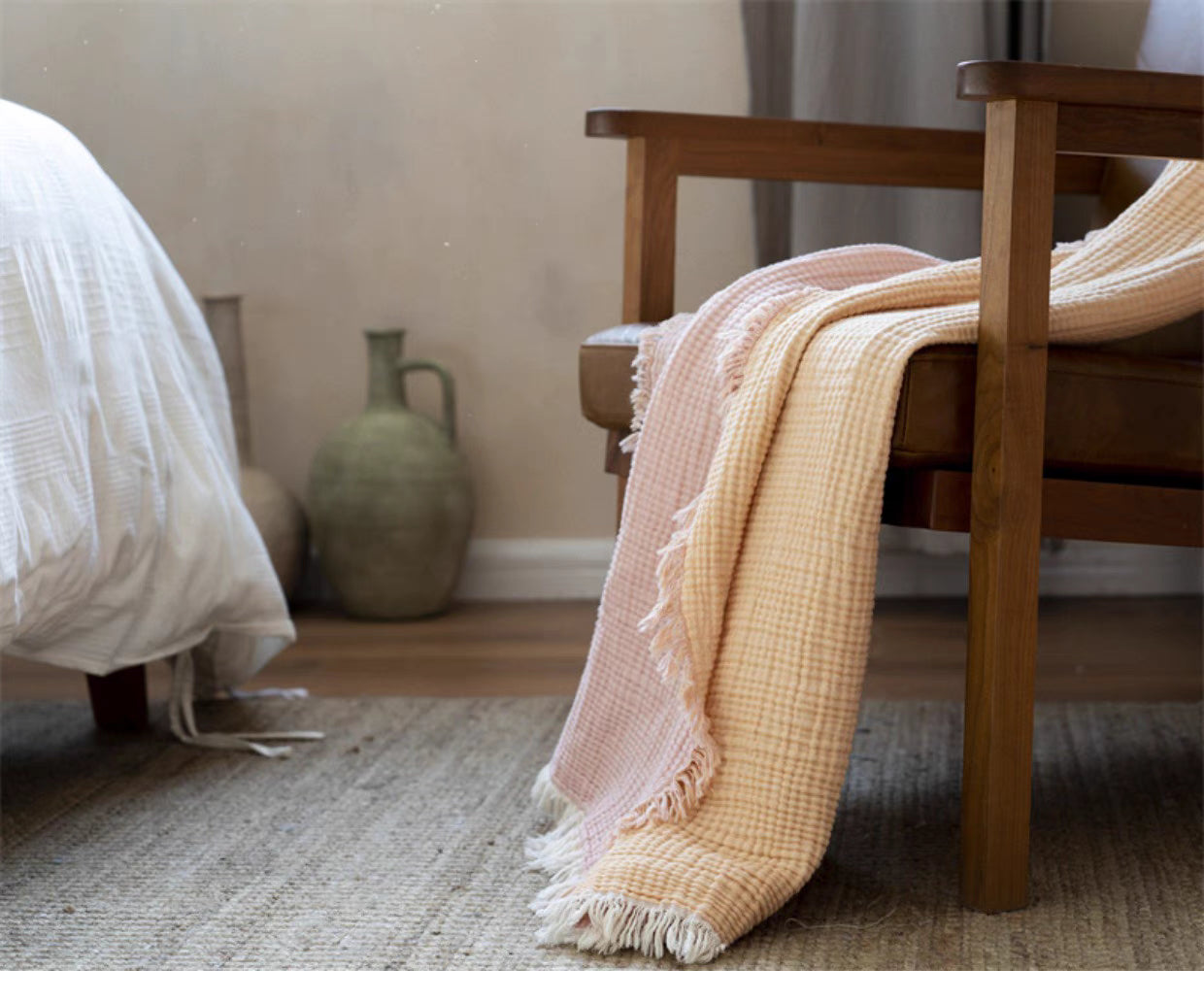 Orange pink reversible cotton gauze throw blanket draped over wooden chair in cozy bedroom setting