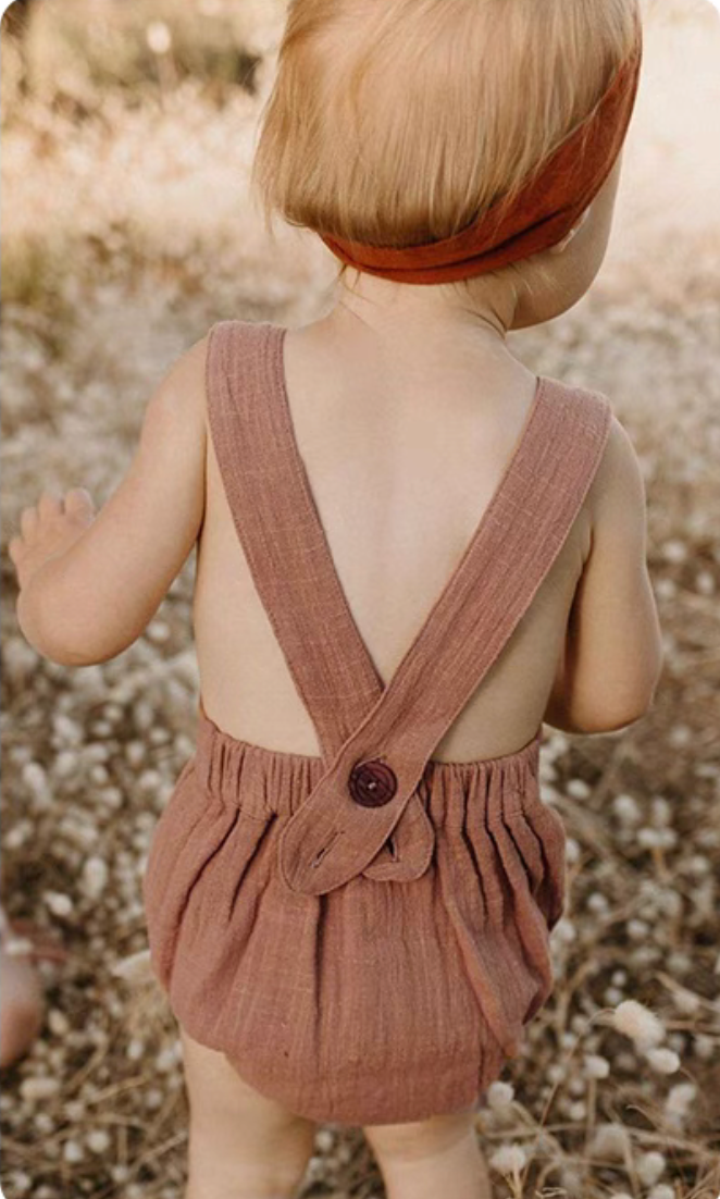 Baby wearing dusty rose cotton gauze romper cross back design soft breathable summer outfit back view