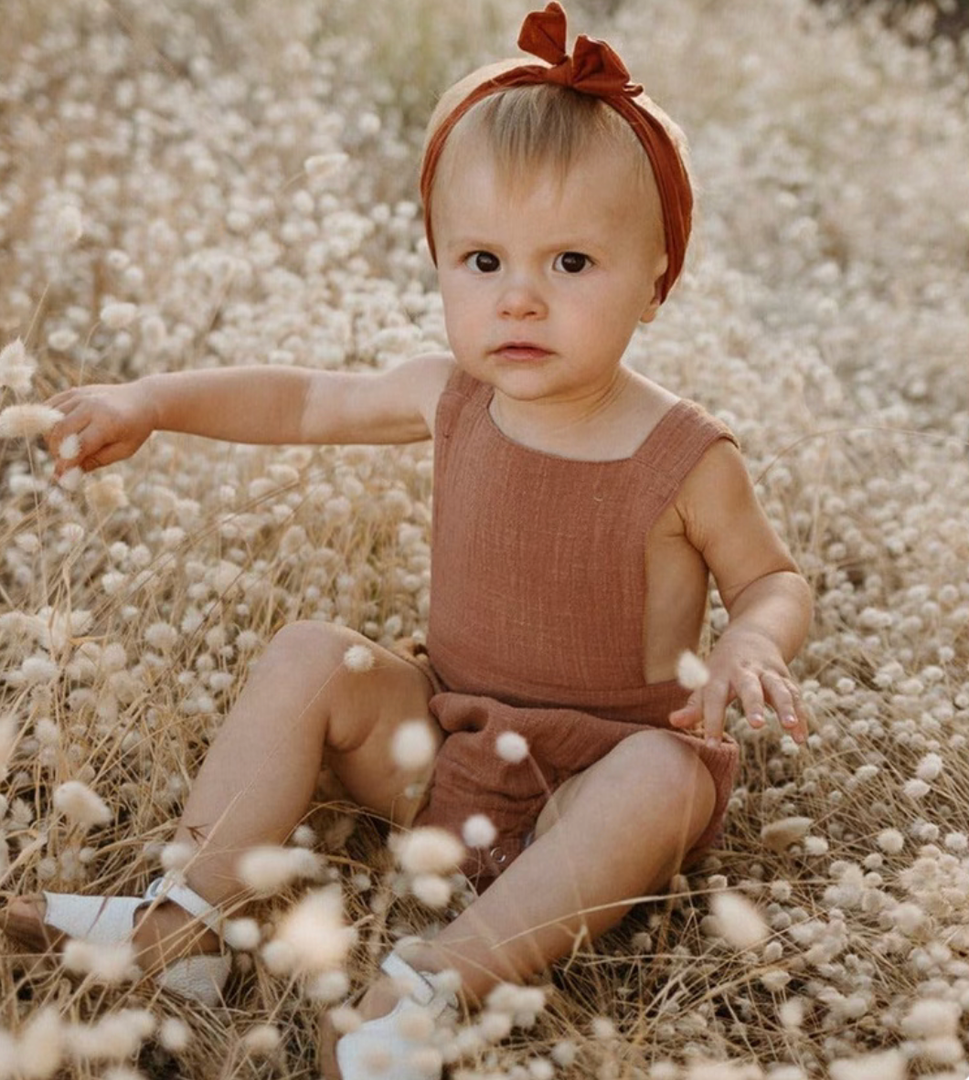 Baby wearing dusty rose cotton gauze romper soft breathable sleeveless summer outfit outdoor lifestyle