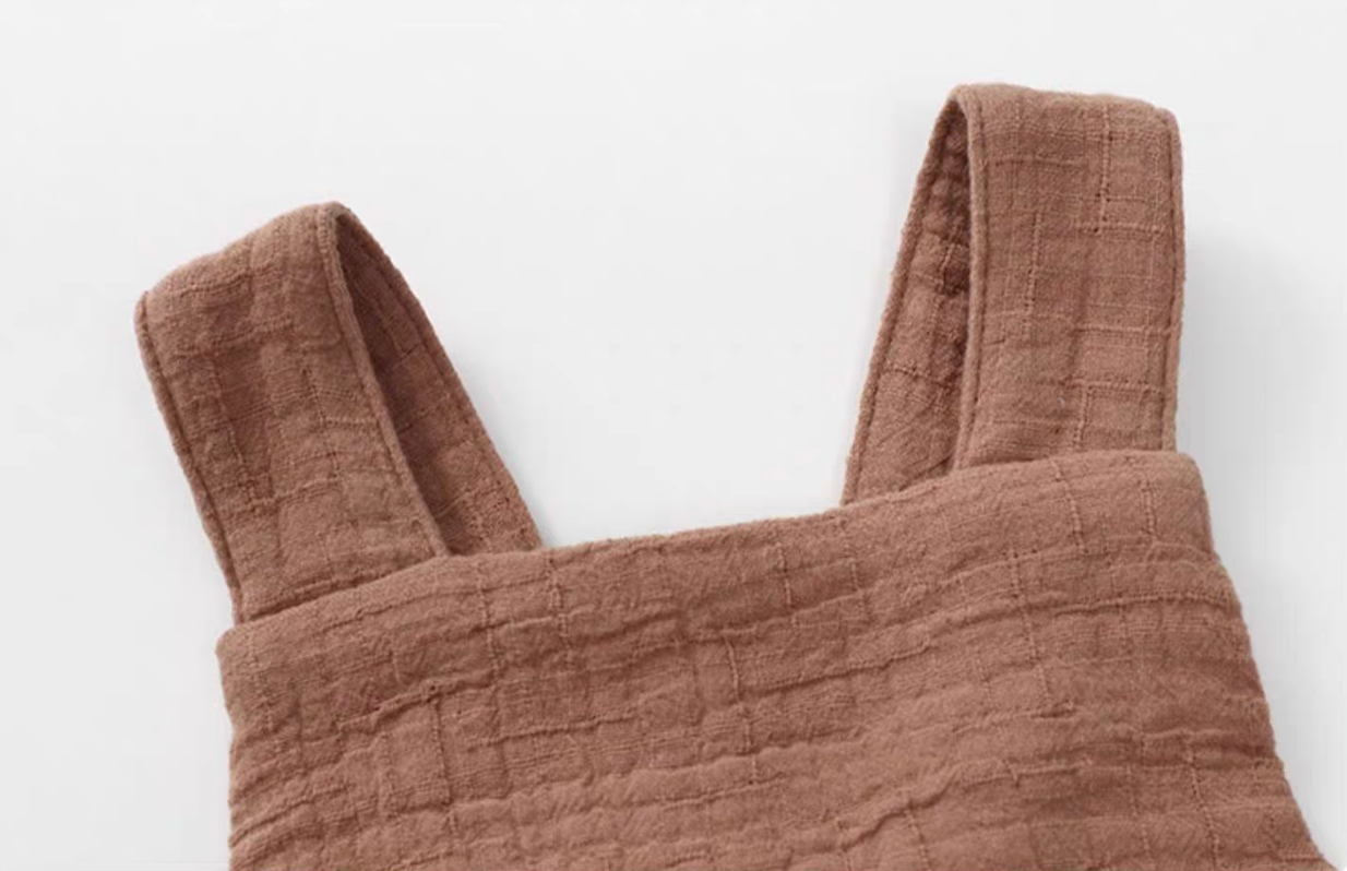 Dusty rose cotton gauze baby romper strap detail close up soft breathable textured fabric