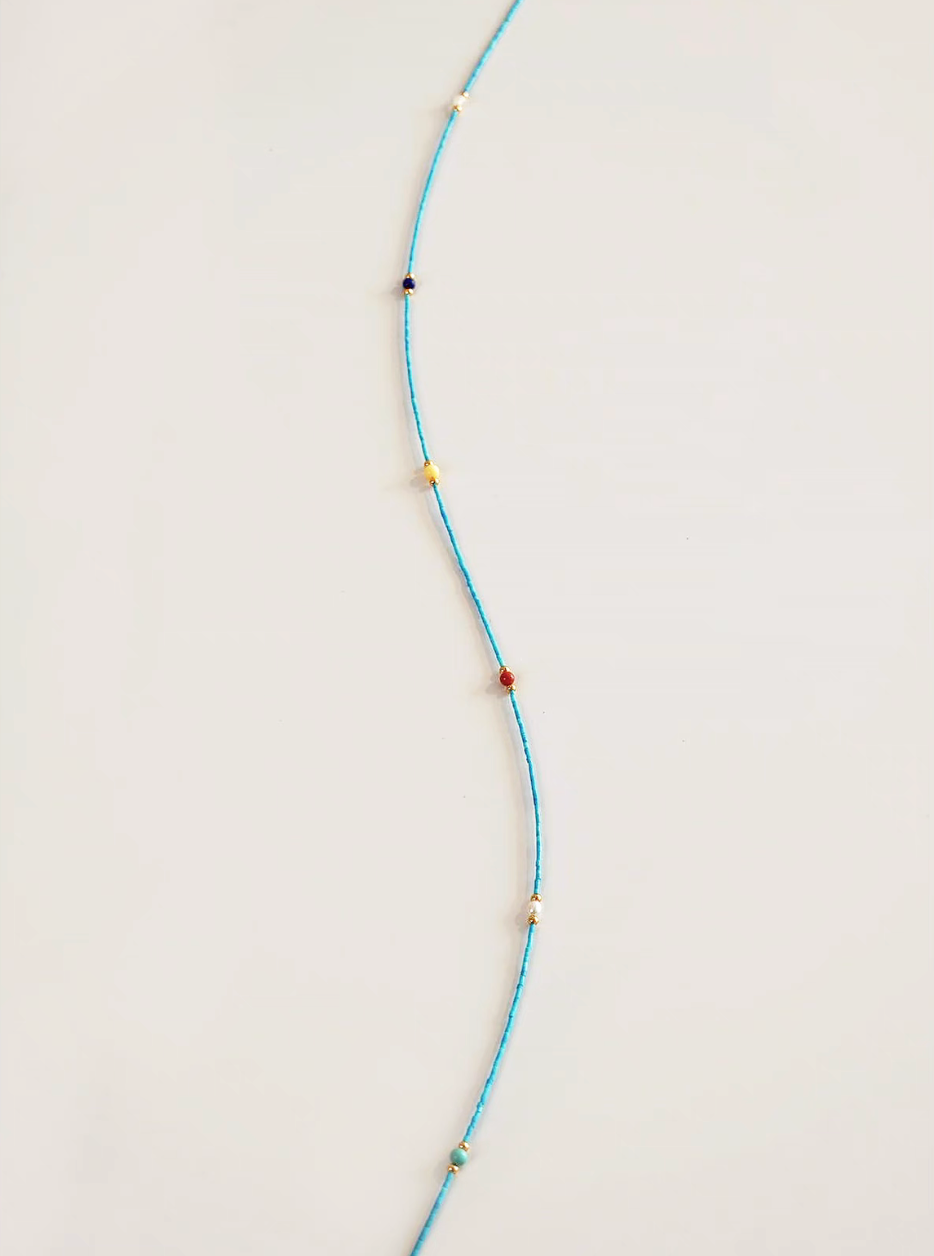 Close-up detail of elegant multi-stone vintage choker showing turquoise strand with red agate, amber, lapis lazuli, and gold-plated accents