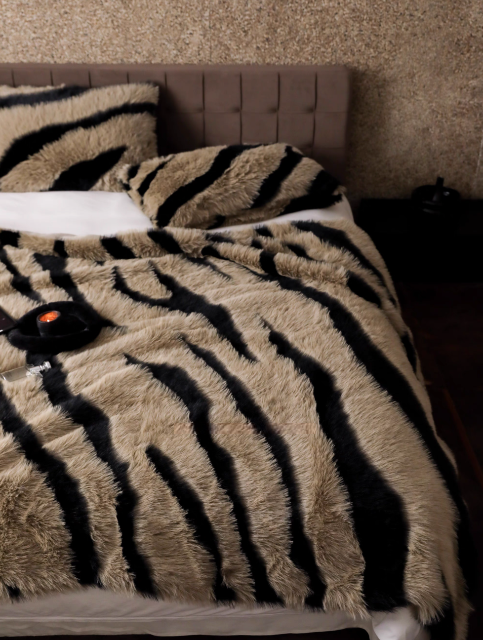 Zebra camel faux fur throw blanket spread across bed with bold animal stripe pattern in warm tones