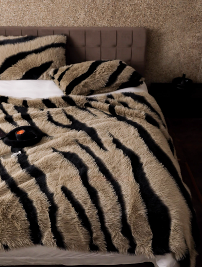 Zebra camel faux fur throw blanket spread across bed with bold animal stripe pattern in warm tones