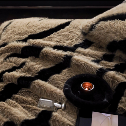 Close-up of zebra camel faux fur throw blanket with soft plush texture beside candle and perfume