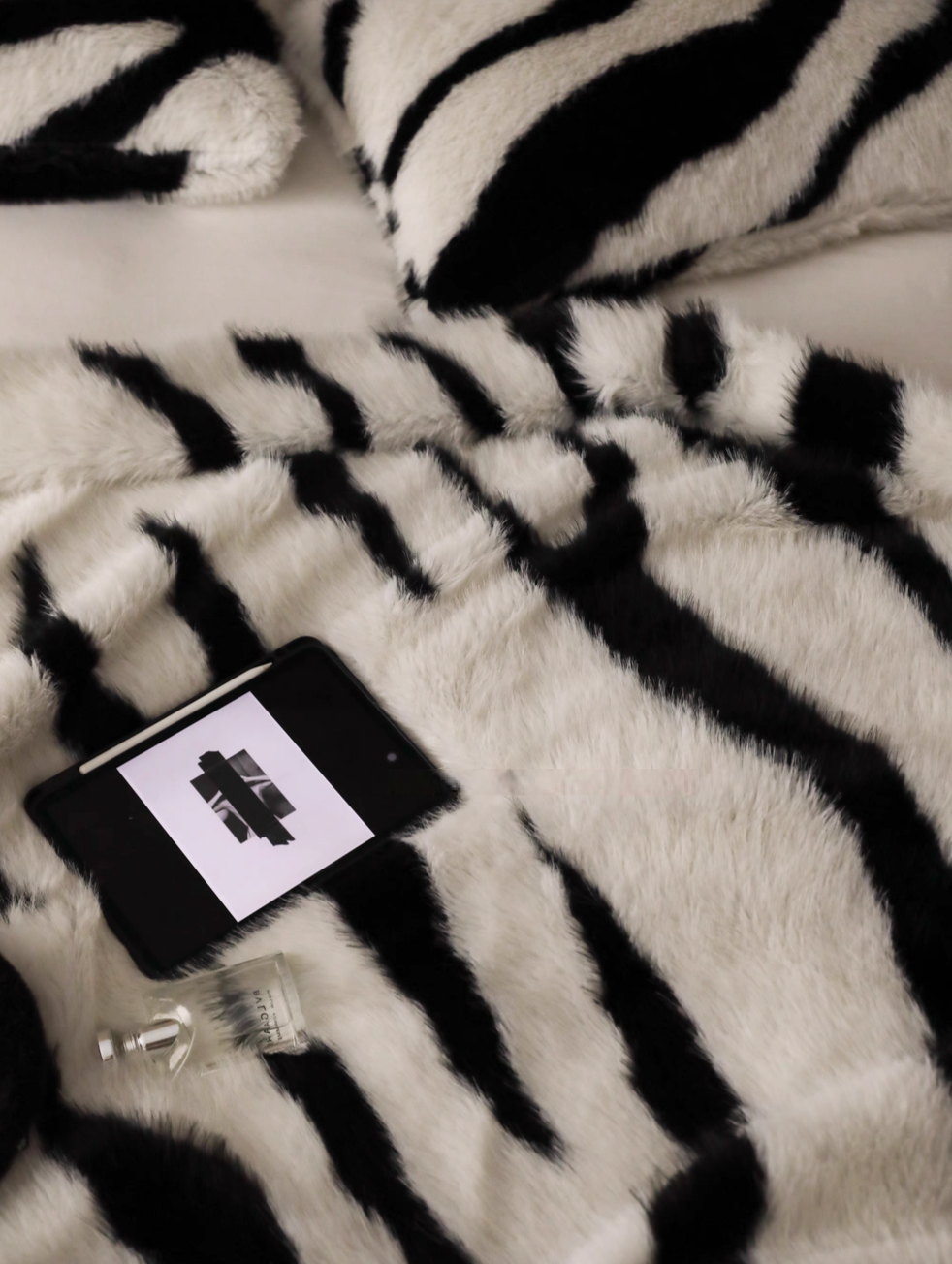 Zebra cream faux fur throw blanket close-up on bed with ultra soft texture and lifestyle accessories