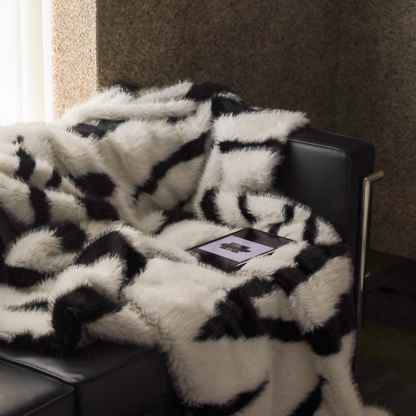 Zebra cream faux fur throw blanket on sofa with soft plush texture and tablet in cozy living space